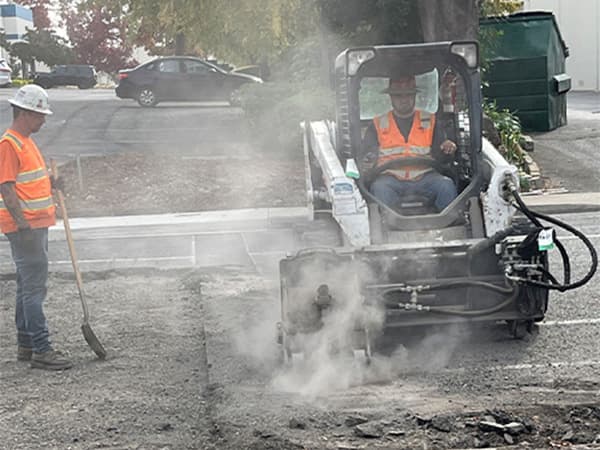 Jeff Smith Construction employee operating heavy machinery to break up pavement at a job site in Sacramento, CA.