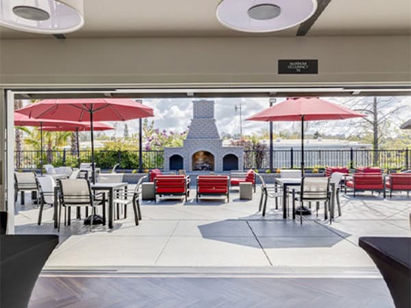 Outdoor area of an HOA clubhouse with tables, chairs, umbrellas, and a fireplace built by Jeff Smith Construction in Folsom, CA.
